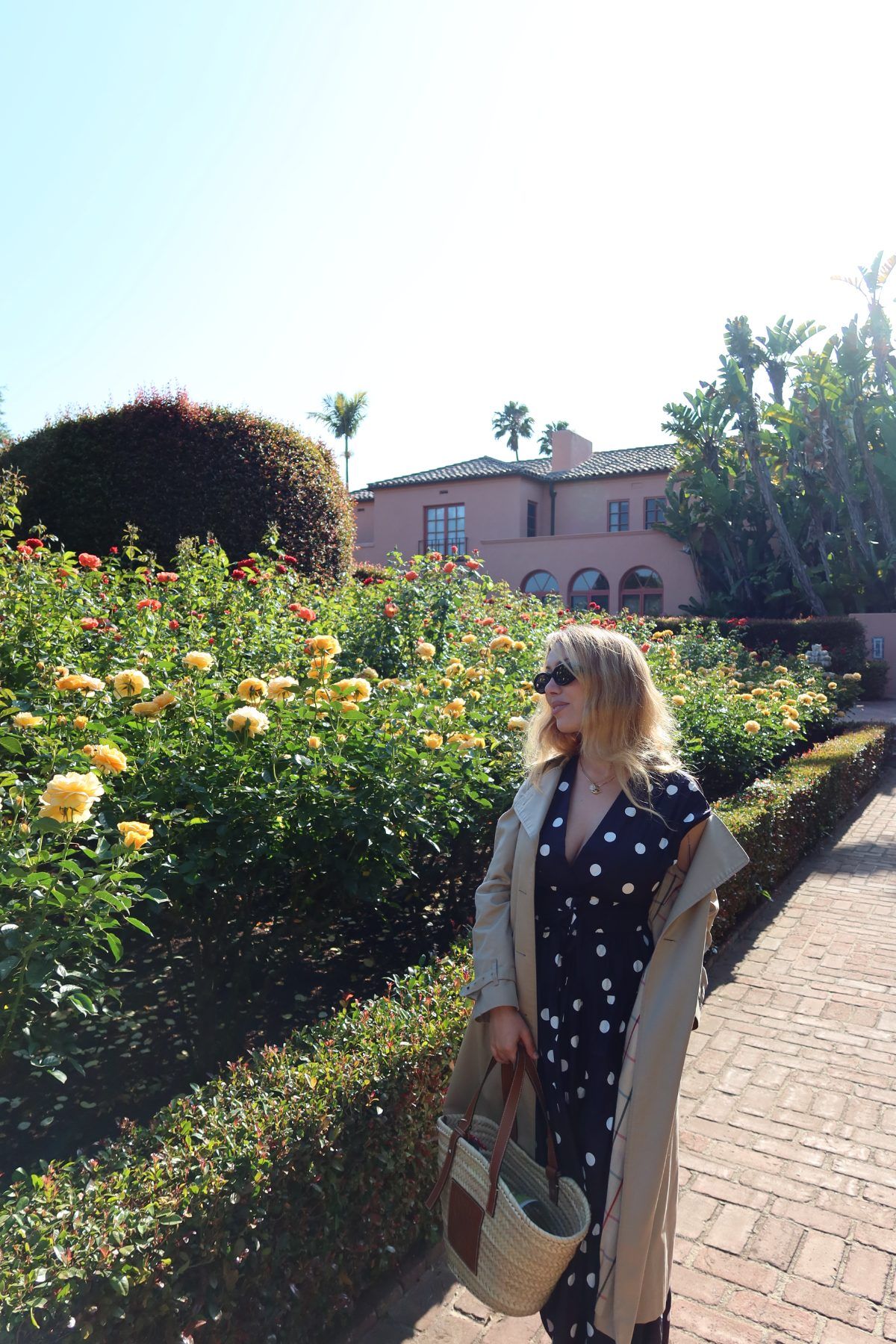Andrea Manokian standing among blooming rose bushes in front of a Spanish-style villa in Santa Barbara.